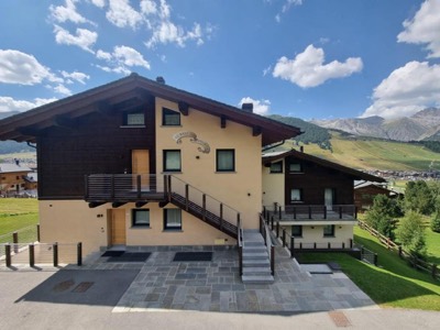 La casa in legno e intonaco chiaro con i balconi, sotto il cielo estivo