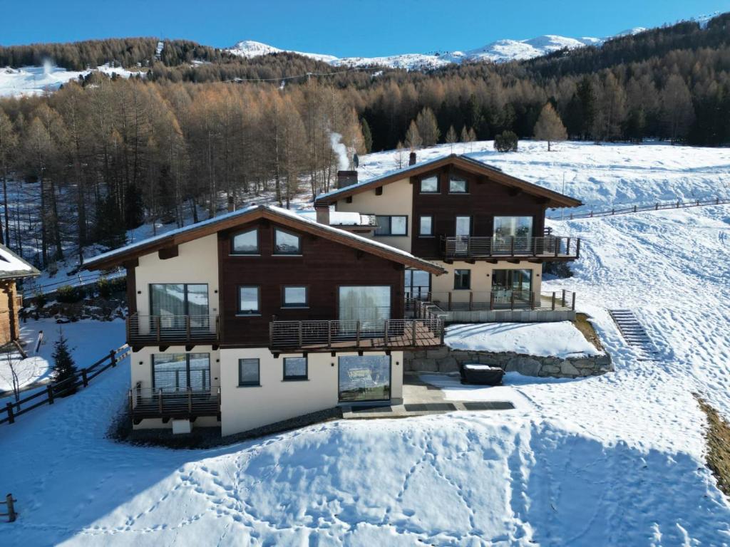 La casa immersa nella neve con il bosco di larici alle spalle