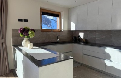 Cucina moderna bianca con isola centrale e piano di lavoro in pietra scura