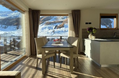 Ambiente unico con cucina, tavolo da pranzo e finestre sulla montagna