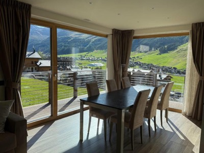 La sala da pranzo con le vetrate aperte sui prati verdi in estate