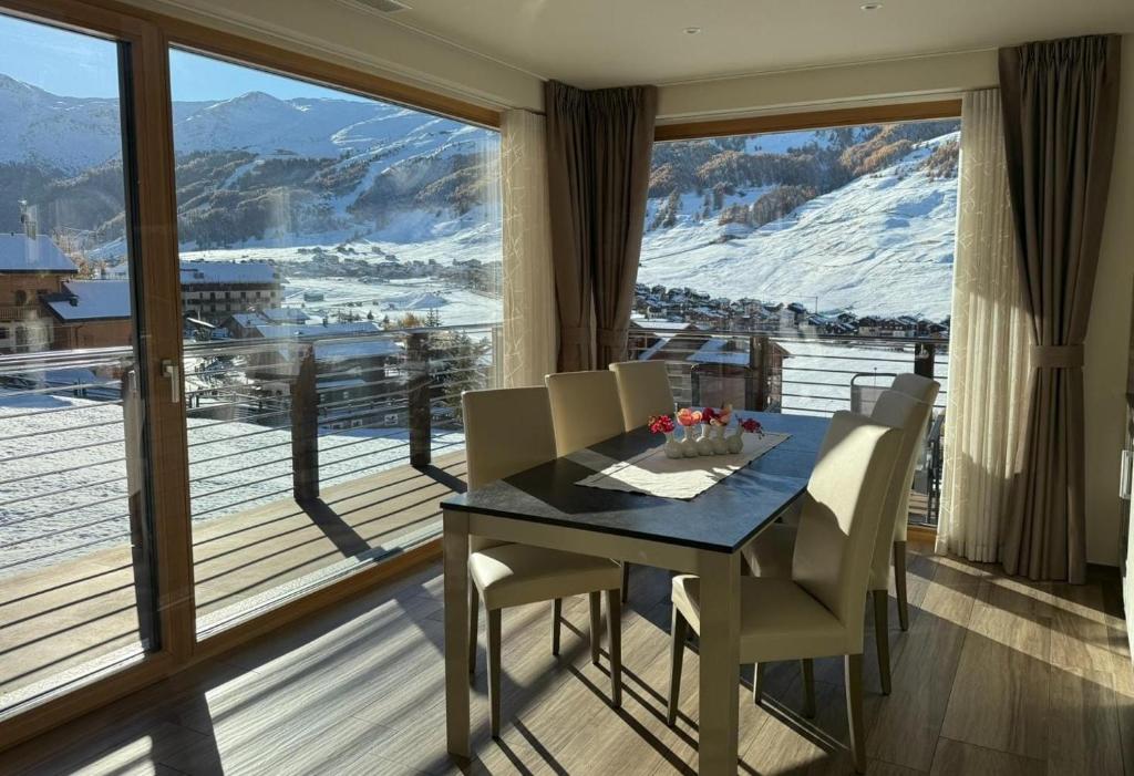 Soggiorno con vetrate ad angolo e accesso al balcone, vista sulla valle innevata