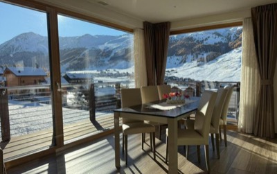Tavolo da pranzo in pietra scura davanti alle vetrate panoramiche